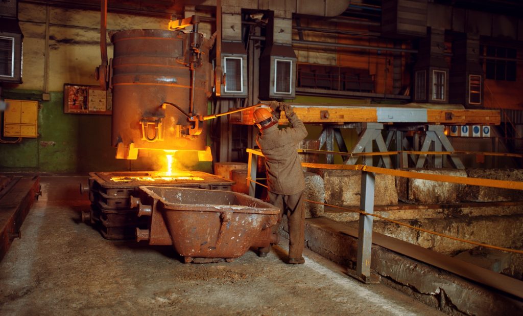 Steelmaker pours liquid metal from basket, factory